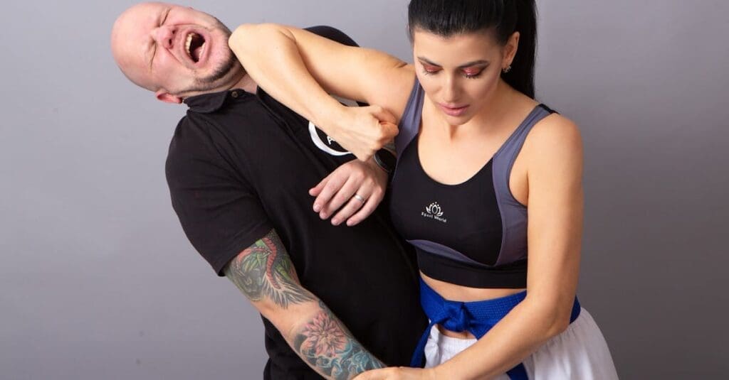 A woman in athletic wear applying a defensive elbow strike and chin grab to escape a simulated attack, demonstrating vital escape tactics for a teen self defense guide.